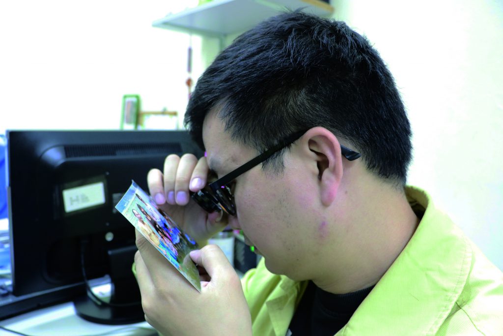 Galant Ng Ka-lun uses a magnifying glass to read.