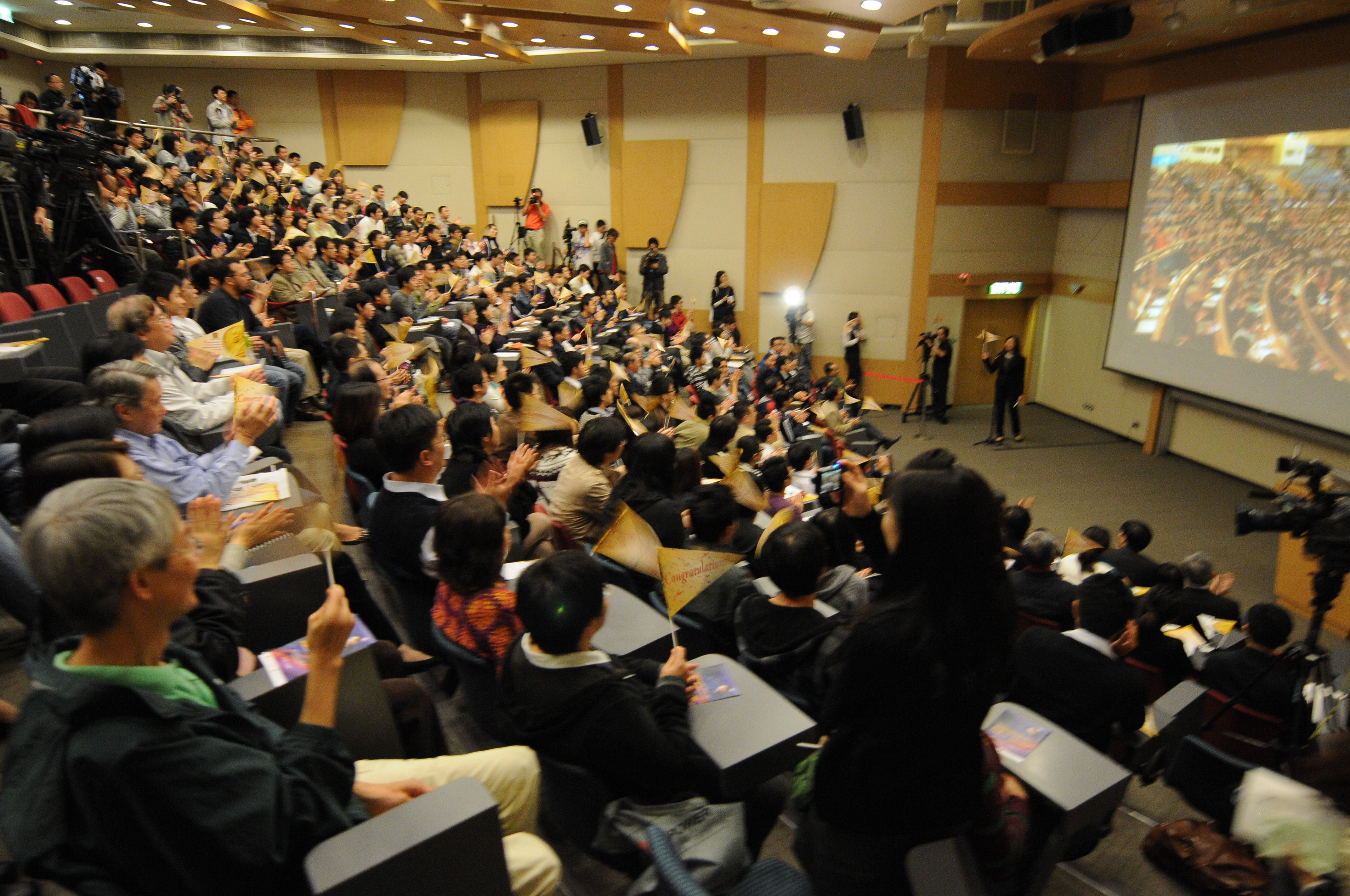 The audience cheers for Professor Kao by waving special mini flags