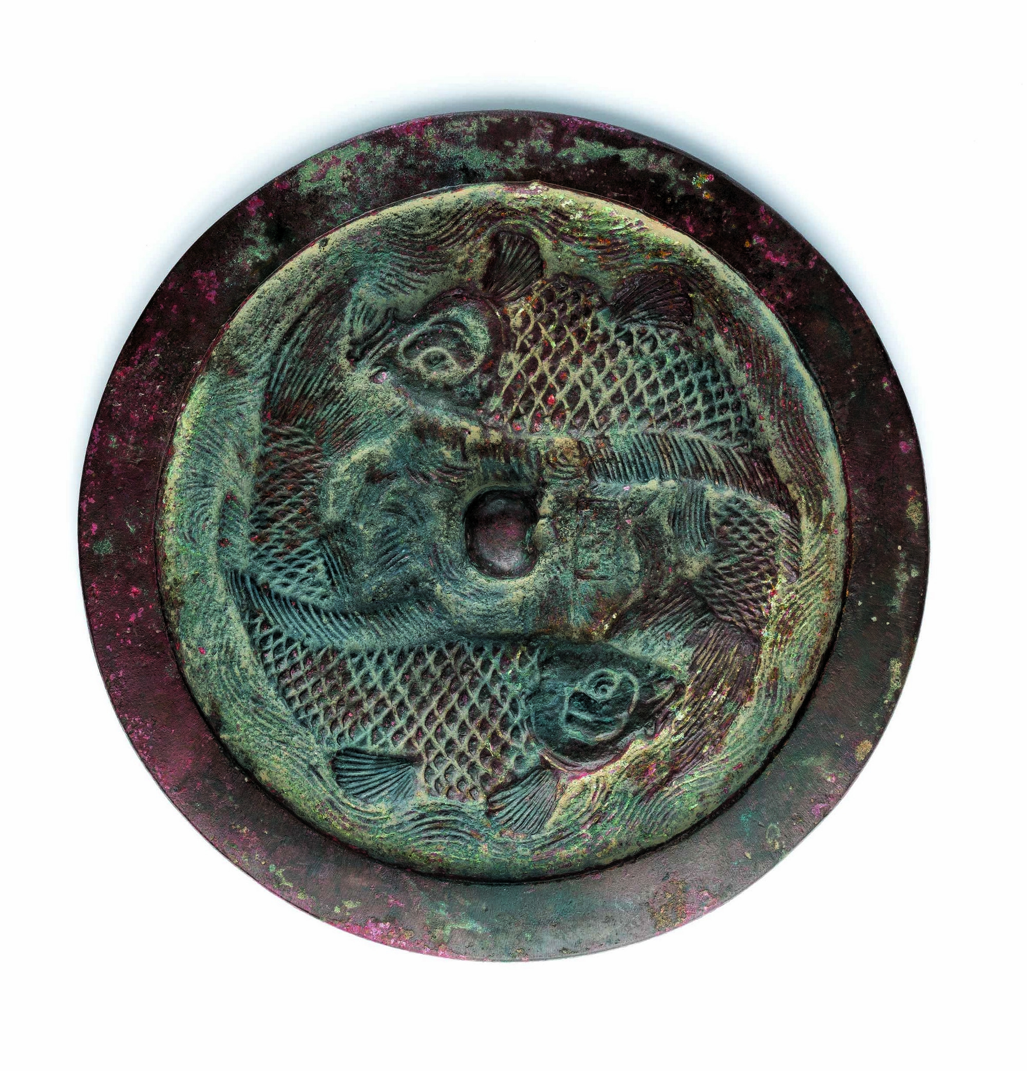 Mirror with a double-fish pattern
Jin, 12th–13th cent.
Diam. 19.4 cm, rim h. 0.75 cm, w. 1508 g
Art Museum Collection 
Gift of Prof. MARK Kai-keung

Mirrors with the double-fish pattern dating to the Jin period were very popular, and their designs, production techniques, and regional features all merit discussion. This mirror has a wide rim; within the circular rim there are two carp-like fish. The wave patterns surrounding the carp and the scales of the carp are carefully carved. This required sophisticated and extremely fine carving skills. We can see their heads and major parts of one side of their bodies. Also, their bodies twist at the end of their tails, and this allows us to see the other sides of their bodies. The fish are vividly represented on the mirror and look like they are playing in the river. The mirror is large, thick, and extremely heavy. It is uncomfortable to hold the mirror by grasping a silk fabric threaded through its loop. Thus, it might have been placed on a stand and is not suitable for a user to hold with two hands to rotate. The mirror might not be a daily reflective object for its users but rather a precious item primarily for display. Similar mirrors have been collected by many museums in China, but clear records of provenance are pointing to the Jilin and Heilongjiang areas. This reflects the popularity of the mirrors in these areas, which fell within the territories of the Jin state.