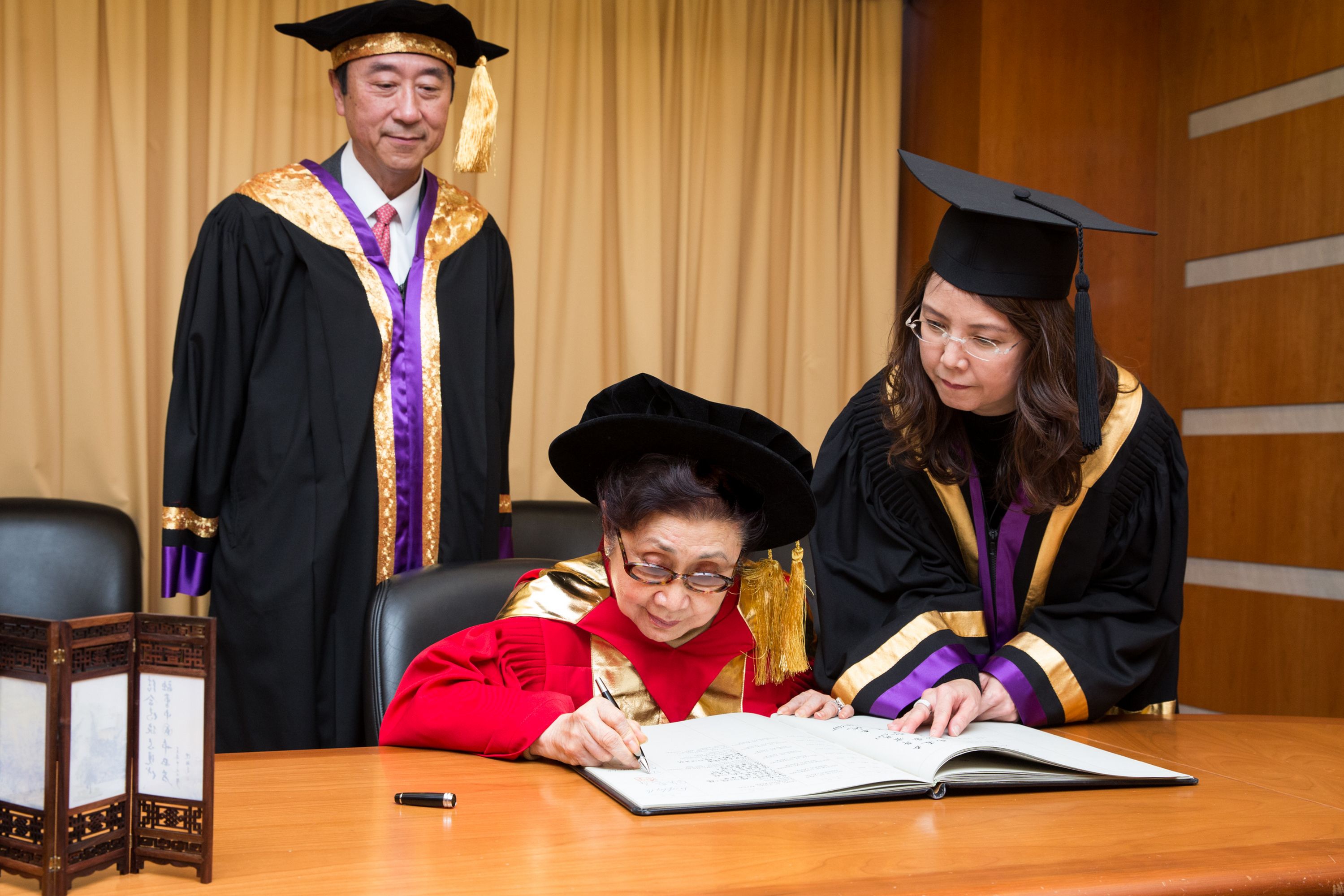 Dr. CHAN Shuk-leung (middle) signs on the Register of Honorary Graduates