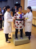 Ms LAM, a 62-year-old who has joined the Jockey Club Programme for Falls & Fractures Prevention for the Elderly, demonstrates the balance test for fall risk assessment with the assistance of medical staff.