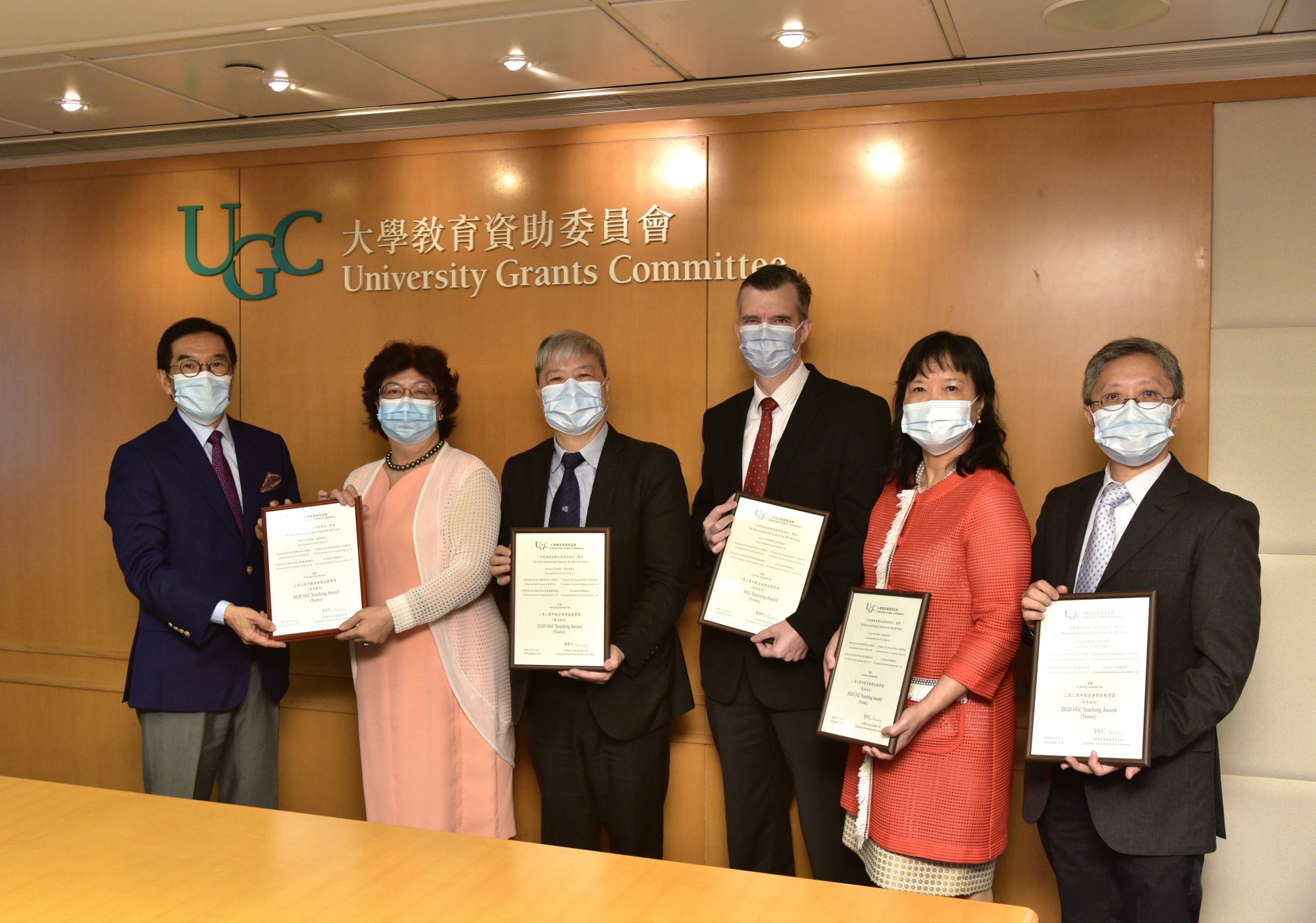 Professor Paul Lai-chuen Lam (first right) and the team receive the award certificate from Mr. Carlson Tong (first left), Chairman of UGC. (Photo provided by the organiser)