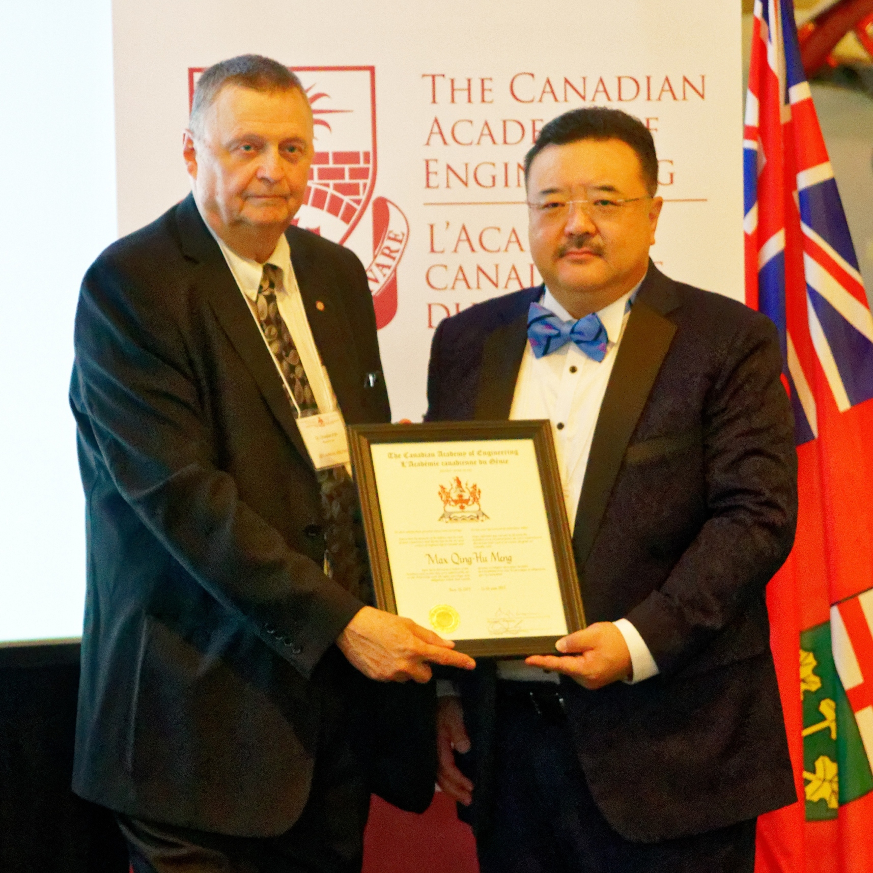 Prof. Douglas Ruth, President of the Canadian Academy of Engineering (left) presents a certificate to Prof. Meng Qing Hu Max.