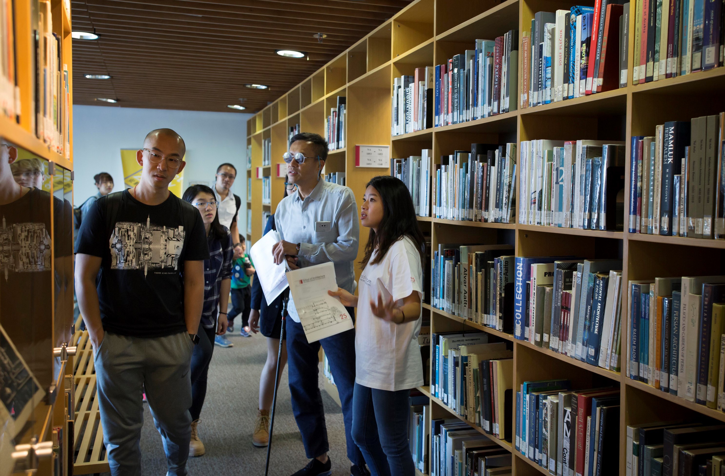 A student docent introducing the Architecture Library to a group of visitors.