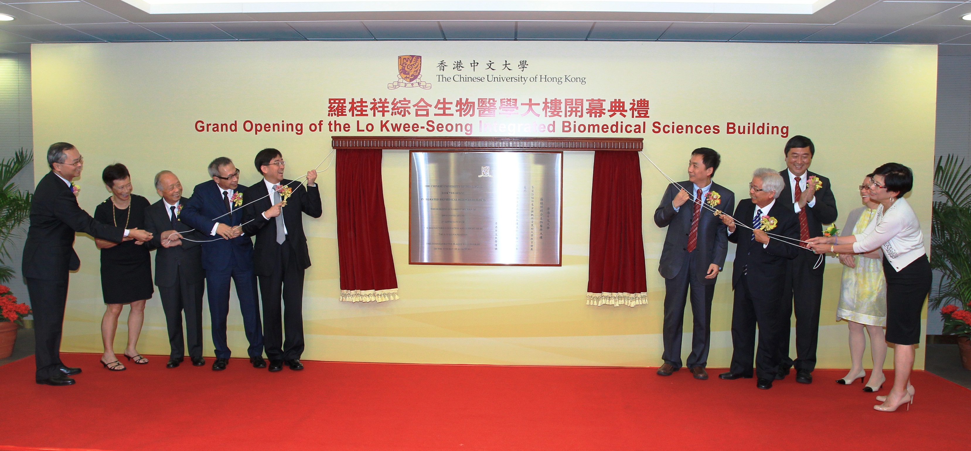 Officiating guests unveil the plaque of the building: (from left) Prof. Fok Tai-fai, Dean of Medicine, CUHK; Mrs. Chan Lo Mo-lin, Irene, Trustee, K. S. Lo Foundation; Mr. Lo Kai-tun, Trustee, K. S. Lo Foundation; Dr. Lo Tak-shing, Peter, Chairman, K. S. Lo Foundation; Dr. the Honorable Ko Wing-man, Secretary for Food and Health, Hong Kong Special Administrative Region; Mr. Wang Zhutian, Assistant Director, China National Center for Food Safety Risk Assessment; Mr. Lo Yau-lai, Winston, Executive Chairman, Vitasoy International Holdings Ltd.; Prof. Joseph J. Y. Sung, Vice-Chancellor and President, CUHK; Ms. Lo Mo-ching, Myrna, Trustee, K. S. Lo Foundation; and Ms. Lo Mo-ling, Yvonne, Trustee, K. S. Lo Foundation.