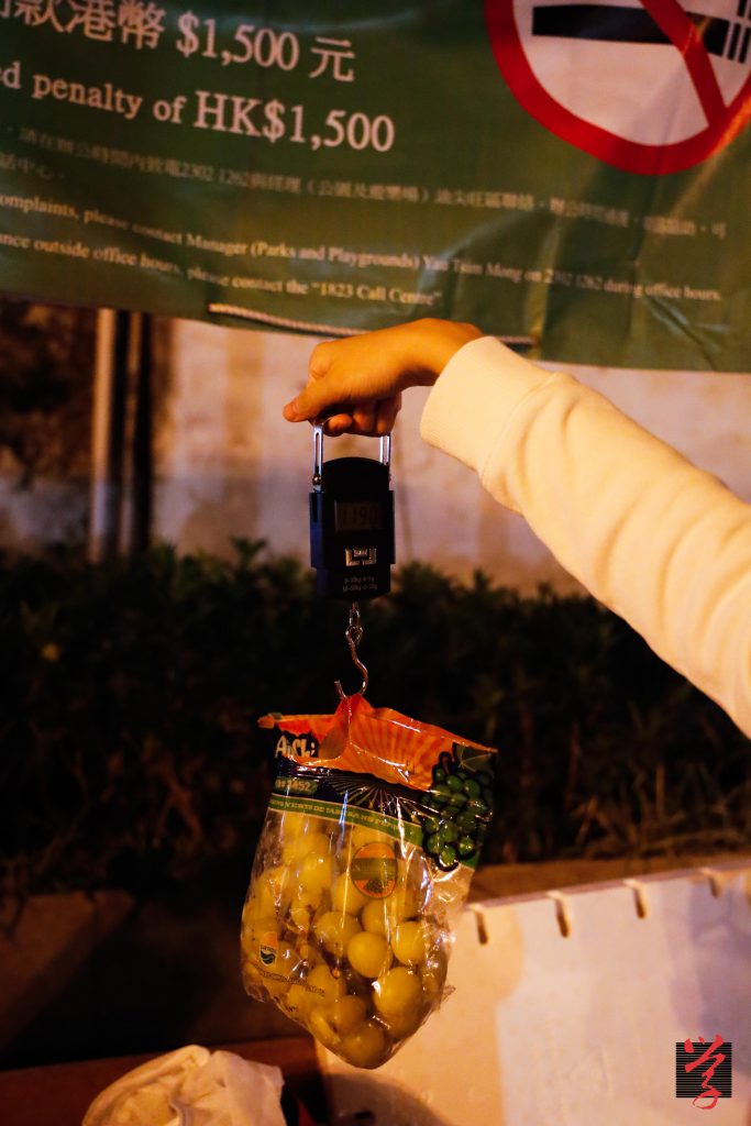 團友會帶備電子磅爲每袋葡萄秤重,再將重量乘以團購時每磅的價格,以計算該袋葡萄的價錢。