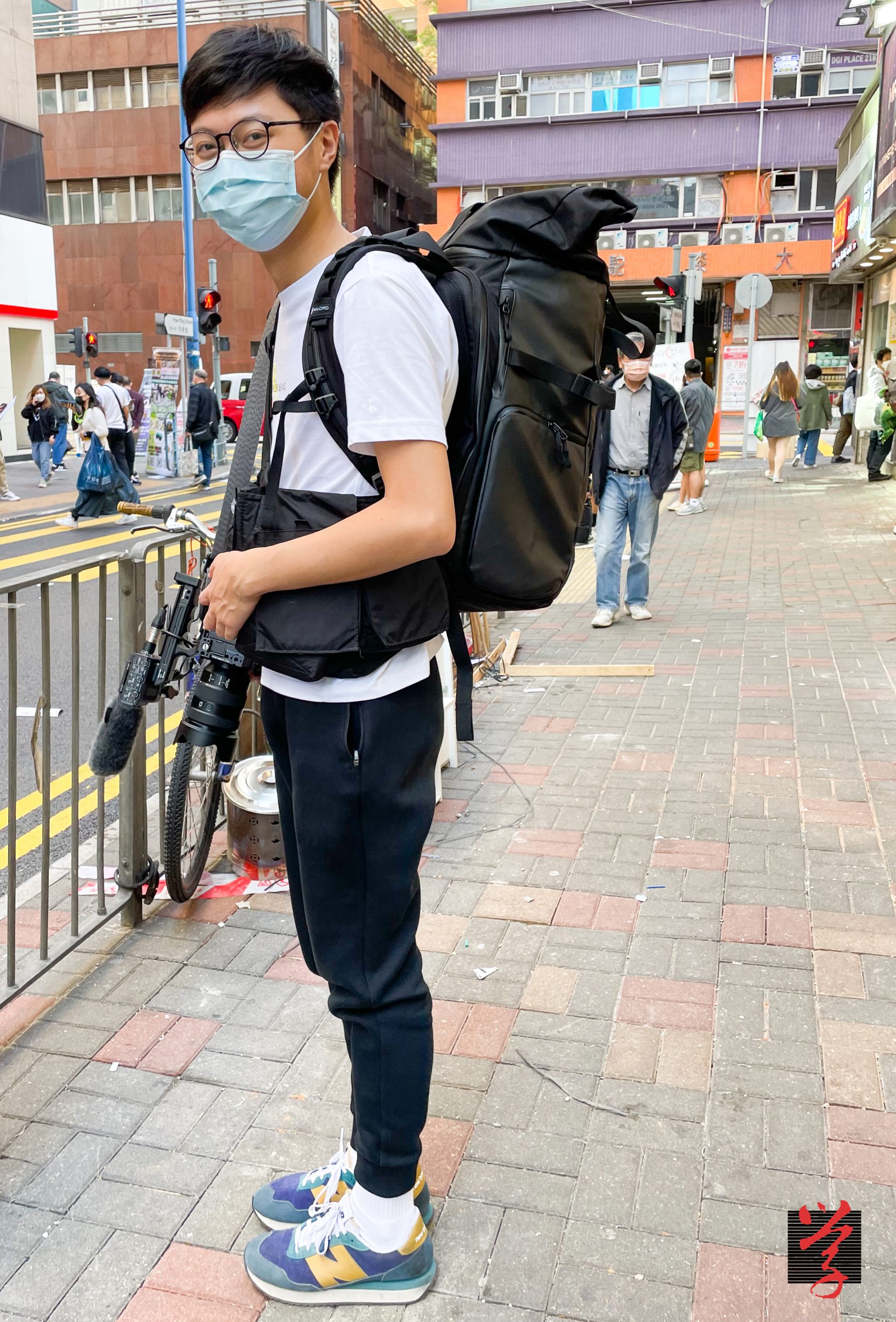 一名機構前記者背起攝影背包,手執攝錄相機,準備啟程拍攝影片。 The WELL 黎家威 一人新聞台