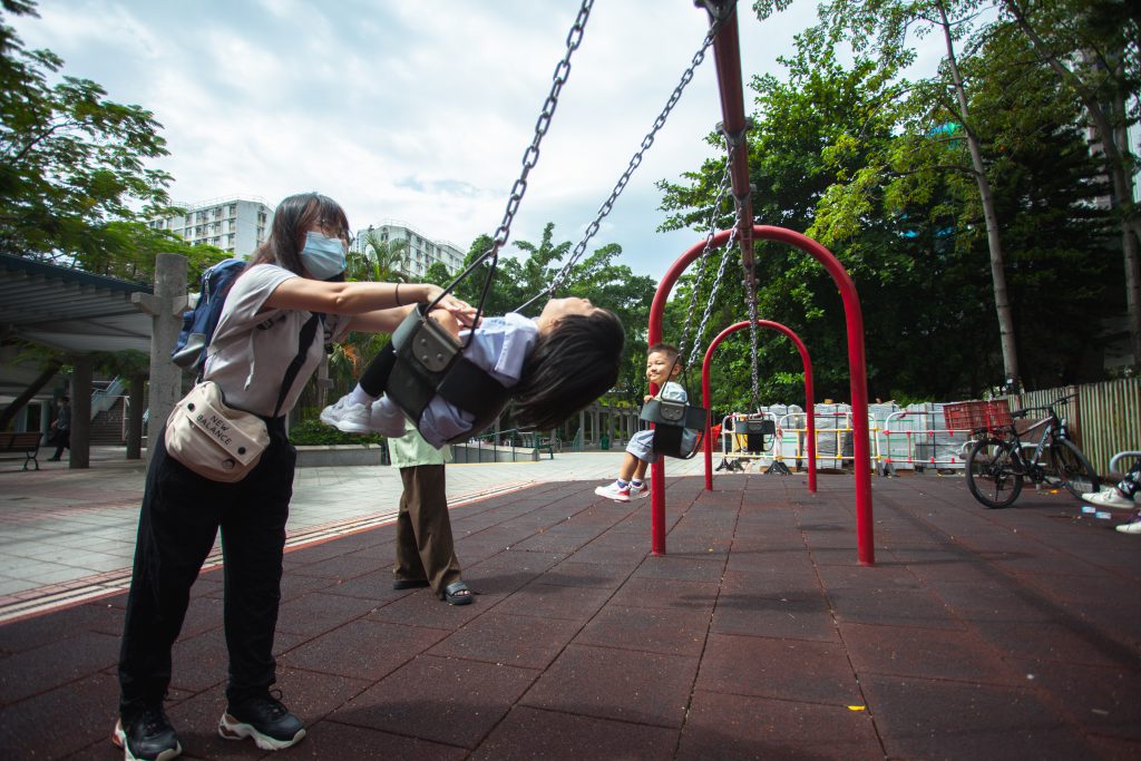 單親媽媽接送女兒放學後，帶她到公園盪鞦韆。