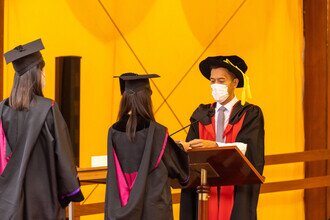 Procession member proudly presenting the graduates on stage