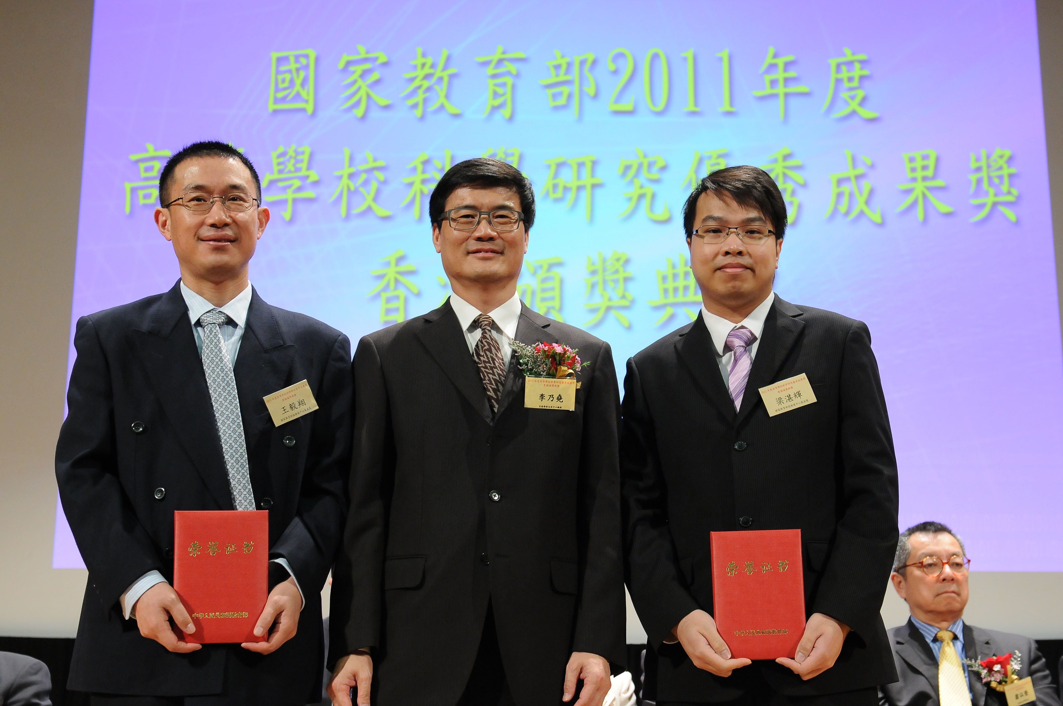 Prof. Wang Yixiang (left), Associate Professor, Department of Imaging and Interventional Radiology; and Prof. Leung Cham-fai Ken (right), Adjunct Assistant Professor, Department of Chemistry, CUHK, receive their award certificates from Mr. Li Naiyiu, President of Beijing-Hong Kong Academic Exchange Center.