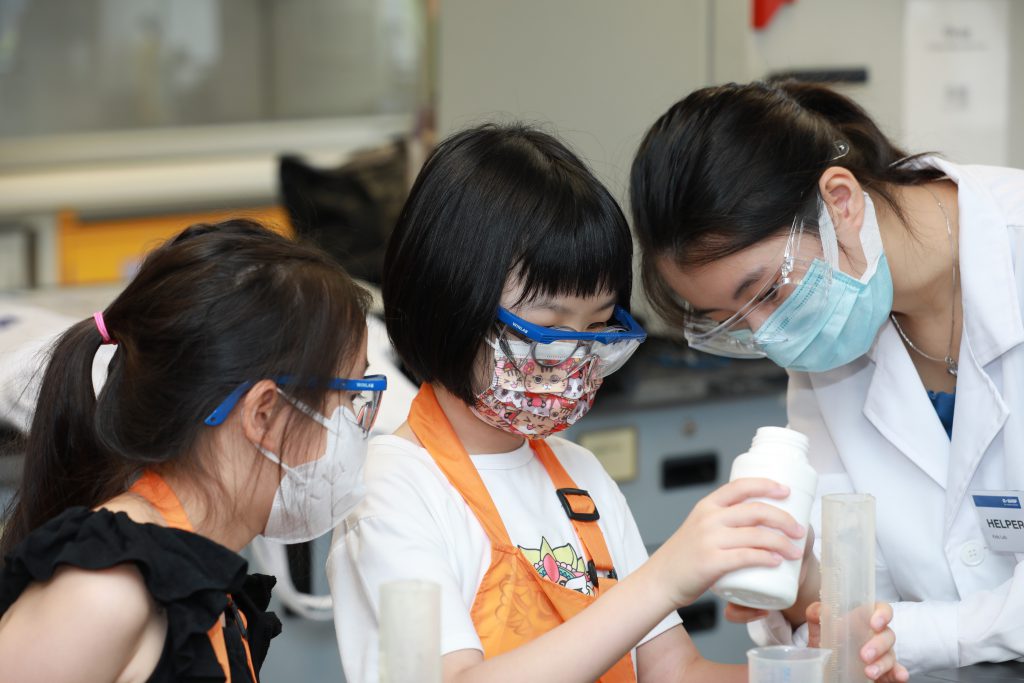 Children making hand sanitiser under the guidance of a CUHK student