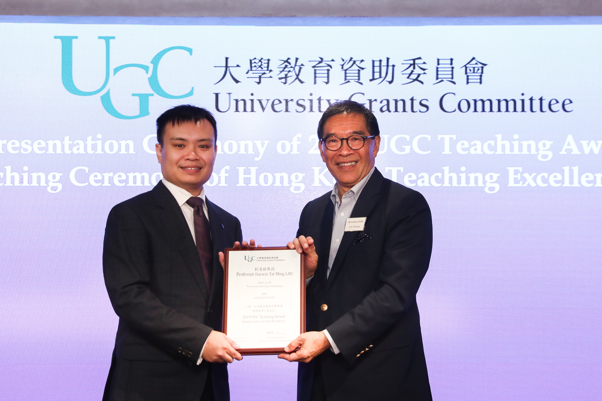 Prof. Darwin Lau receives the award certificate from Mr. Carlson Tong, Chairman of UGC.