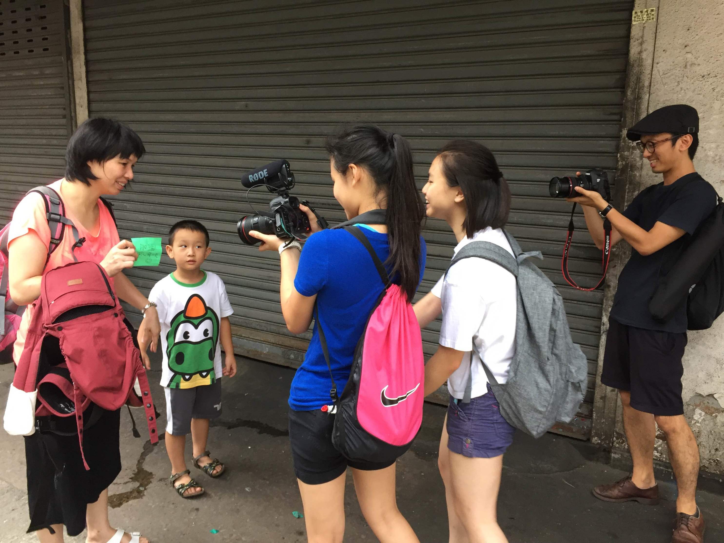 两位参加计划的学生走出课室，与土瓜湾街坊进行录影访问。