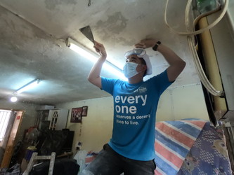 A student scrapes off peeling paint from the ceiling